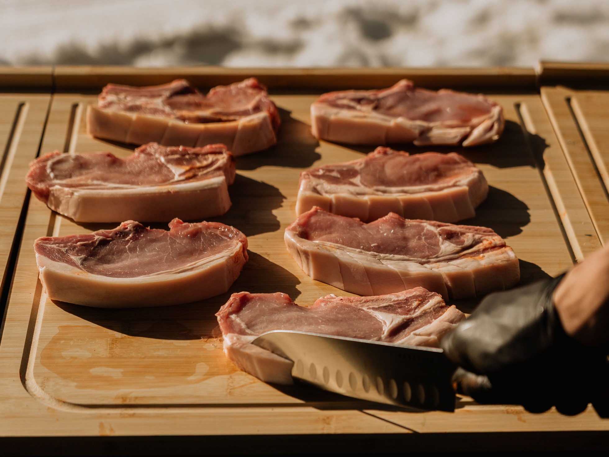 Découpe d'une côte de porc épaisse sur planche en bois